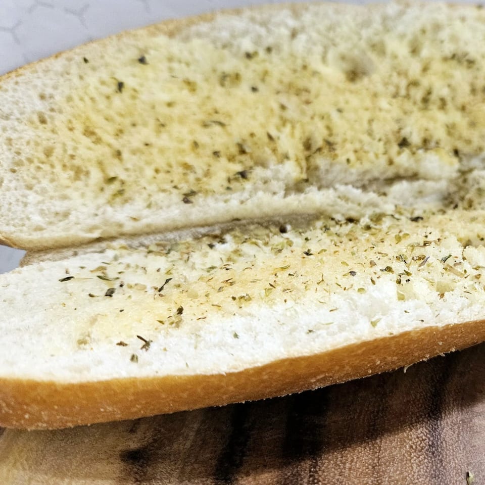 Two halves of garlic bread, seasoned with herbs, ready to be served at Lagos Island Pizza & Grille.